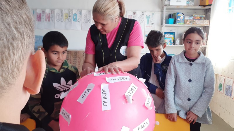 Educadora e crianças em atividade de reforço escolar na ACRICA